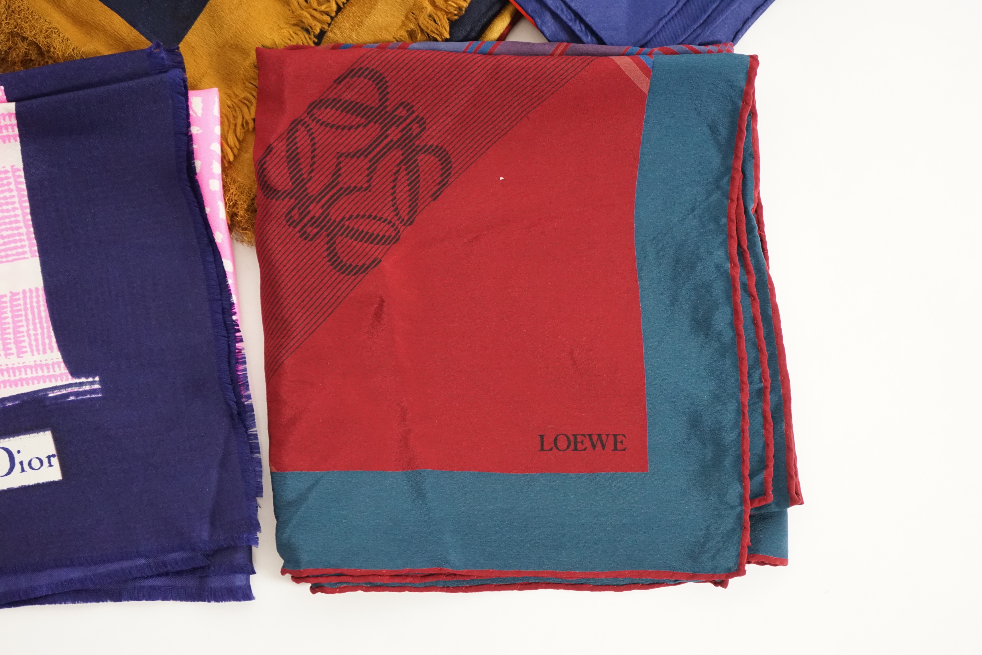 A selection of Yves Saint Laurent, two Christian Dior, Richel and Loewe silk scarves, YSL, 83cm x 85cm Christian Dior: 84cm x 80cm Richel: 87cm x 87cm Loewe: 86cm x 82cm Christian Dior large scarf 120cm x 130cm approx.